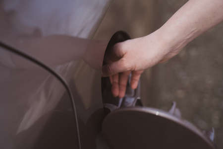 The fuel tank of the car is close-up. Woman fills up the car with fuel and closes the tank