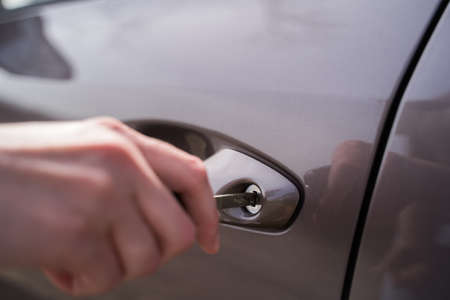 Close-up - the person opens the car door with a key of gray color