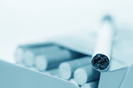 Close-up view of cigarette lying on pack. Blue tonedの写真素材