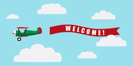 Vintage airplane with banner Welcome on blue sky with clouds backgroundの写真素材