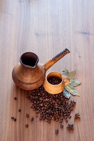 Coffee beans spilled on a wooden table with spices with a cup and coffee maker. Great background for cafe menu design.の写真素材