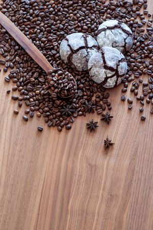 Spread on a wooden table coffee beans with spices with three cakes. With a wooden spoon. Great background for cafe menu design.の写真素材
