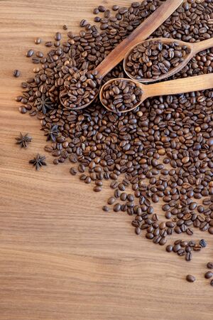 Coffee beans spilled on a wooden table with spices with three wooden spoons. Great background for cafe menu design.の写真素材