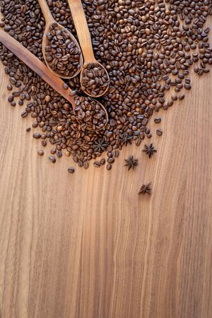 Coffee beans spilled on a wooden table with spices with three wooden spoons. Great background for cafe menu design.の写真素材