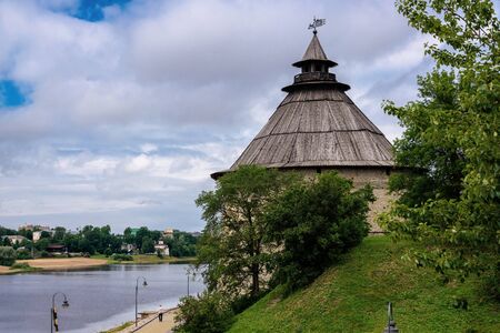 View of a watchtower of the Pskov Kremlin from the bridge through the river in summer dayの写真素材