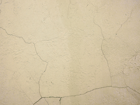 The old plastered background on a building wall with cracks and chipsの写真素材