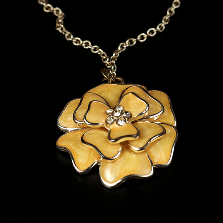 Yellow pendent in the form of a flower, costume jewelry, close up on a black background.の写真素材