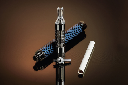 Vape, electronic cigarette exploded next to a conventional cigarette on a dark background with a gradient.の写真素材