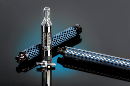 Vape, electronic cigarette exploded next to a conventional cigarette on a dark background with a...