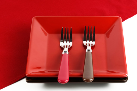 Red plate and two forks on a red napkin.の写真素材