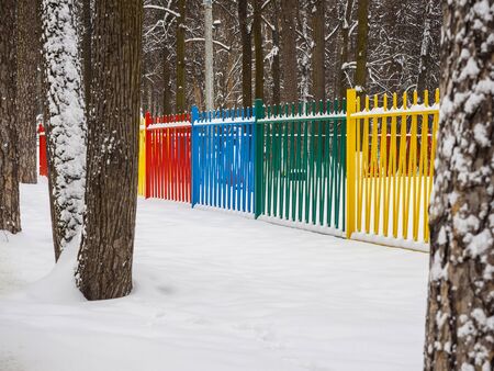 Colored metal fence in a park in the snow.の写真素材