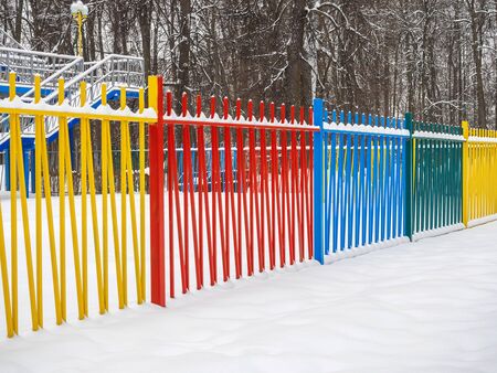 Colored metal fence in a park in the snow.の写真素材
