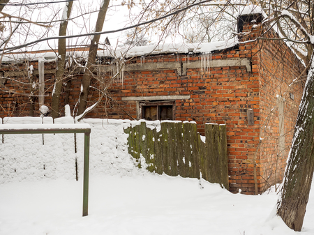 The old brick building behind a wooden fence in winter.の写真素材