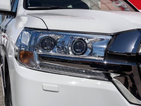 Car headlight of a new white car with chrome trim.の写真素材