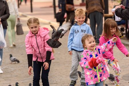 Children feed pigeons on a square in Vitebsk. Belarus, June 2017.のeditorial素材
