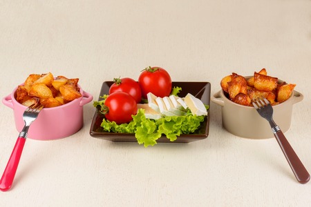 Breakfast from cheese, tomatoes, potatoes and all-over salad on a wooden table closeup.の写真素材