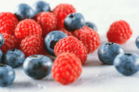 Blueberries and raspberries mix on the background of gray cement. Ripe and juicy fresh raspberries...