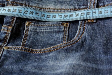 Blue jeans and a blue measuring tape close-up. Measurement of size. Diet and healthy.の写真素材