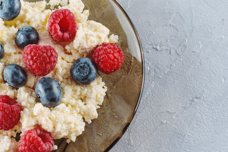 Cottage cheese with fresh raspberries and blueberries in a plate for a healthy breakfast with ripe berries. A natural healthy product.の写真素材