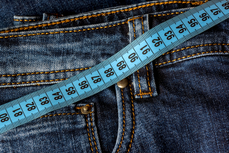 Blue jeans and a blue measuring tape close-up. Measurement of size. Diet and healthy.の写真素材