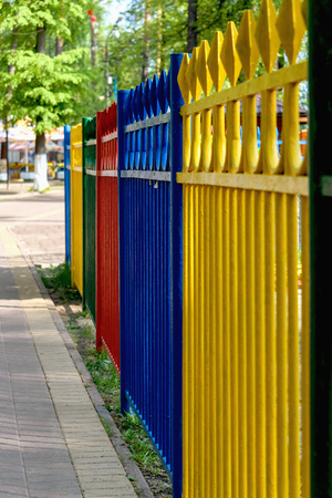 Multi-colored metal fence in the park around the children's rides.の写真素材