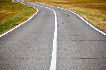 Road in a field on a summer day. Asphalt road for cars in the field.の写真素材