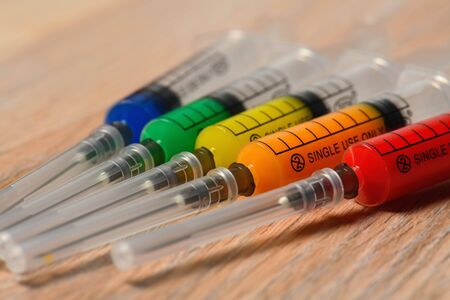 Concept photo of the COVID virus vaccine search. Syringes with different color filling.の写真素材