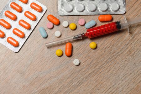 Concept of treatment options for COVID virus infection. Colorful syringes and tablets close-up.の写真素材