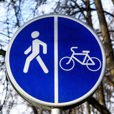 Round blue sign "Pedestrian and Bicycle path" close-up. A sign that divides the path for pedestrians and bicyclists.の写真素材
