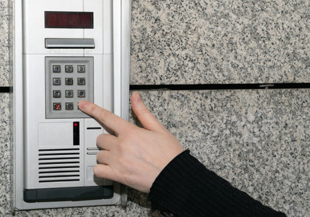 secure home system. Hand pressing on intercom keypad, using door phone, doorphone, entryphone,...