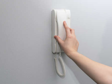Hands opening door through intercom. Using door bell phone, doorphone, entryphone, videophone call