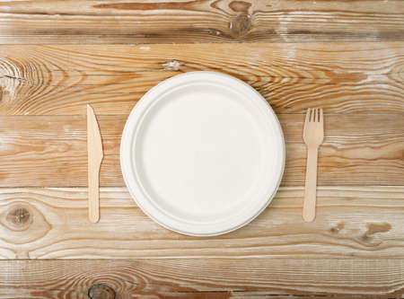 Paper plate, fork, knife on wood table. Eco tableware, disposable cutlery, biodegradable, eco bio...