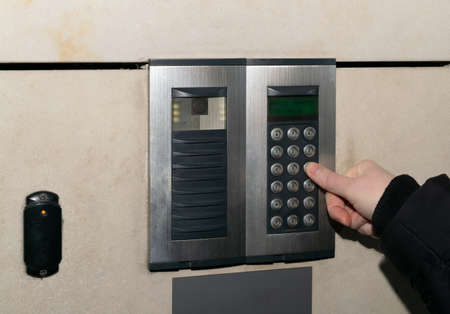 secure home system. Hand pressing on intercom keypad, using door phone, doorphone, entryphone,...