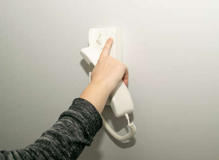 Hands opening door through intercom. Using door bell phone, doorphone, entryphone, videophone call