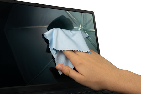 Wipe laptop screen isolated. Open laptop monitor wiping, hand cleaning pc with blue cloth, computer care, cleaning black device on white background closeupの写真素材
