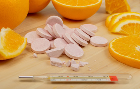 Effervescent orange tablets with medical thermometer. Fizzy fruit tablets pile, disease prevention...