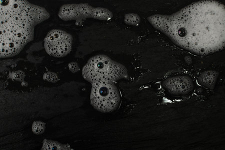 Detergent foam texture background. Lather pattern, soap bubbles on black stone surface, soap foam wallpaper with copy spaceの写真素材