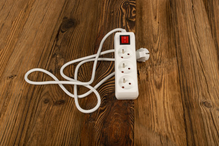 Power strip on wooden background. Extension cable, electricity strip, home socket, white power extender, extension cord on wood flooringの写真素材