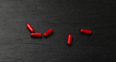 Red pills on black plate. Capsule set , analgesic, painkiller drugs, sedative pill collection,...