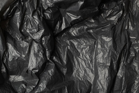 Crumpled garbage bag texture background. Trash package pattern, wadded up plastic bin bags, black...