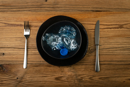 Eat Plastic, Blue Empty Plastic Bottle on Plate, Crumpled Plastic Bottle, Global Pollution Concept, Squashed Water Pet Bottles on Wood Backgroundの写真素材