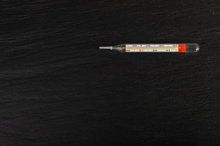 Medical Thermometer on Black Background, Temperature Measuring, Fever, Glass Medical Thermometer Top View, Copy Spaceの写真素材