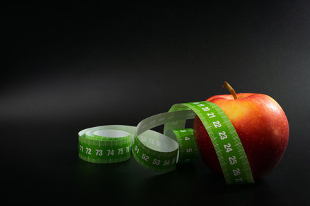 Red Apple and Measuring Tape, Measure Tapes, Metric Tape on Black Background, Health Diet Food,...