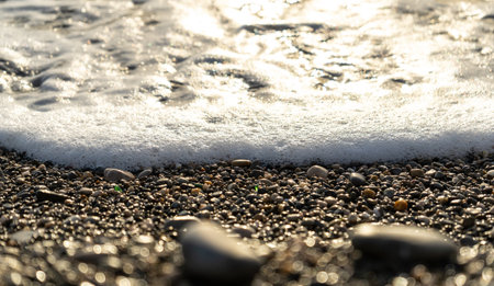 Sea waves on pebble beach texture background. Transparent ocean water, rocky shore pattern, summer mockup with copy space, stone shoreline, vacation conceptの写真素材