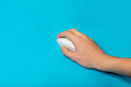 Using Computer Mouse Closeup, Click Concept, Wireless Technology, Hand on White Computer Mouse on Blue Backgroundの写真素材