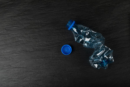 Blue Empty Plastic Bottle on Black Background, Crumpled Plastic Bottle, Global Pollution Concept,...
