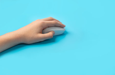 Using Computer Mouse Closeup, Click Concept, Wireless Technology, Hand on White Computer Mouse on Blue Backgroundの写真素材