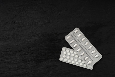 Pill Blister on Black Stone Background, Silver Capsule Package Mockup, Drugs Packaging Banner, Pill Pack, Pharmacy Box, Medicine Capsules Blisters Top View, Copy Spaceの写真素材