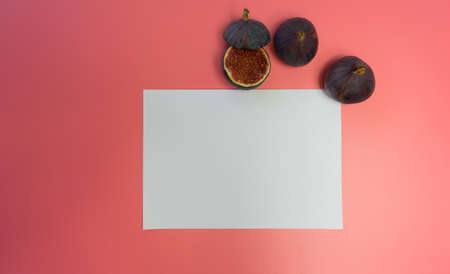 work table with blank sheets and pen, sliced fresh juicy figs, pink background. Planning concept,...