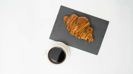 Top view or flat lay of coffee cup and croissant on white background with copy space. Morning coffee and snack.の写真素材